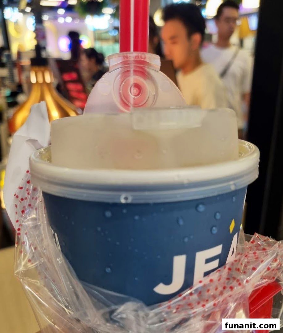 Close-up of a refreshing beverage cup with a straw, held in a plastic bag.