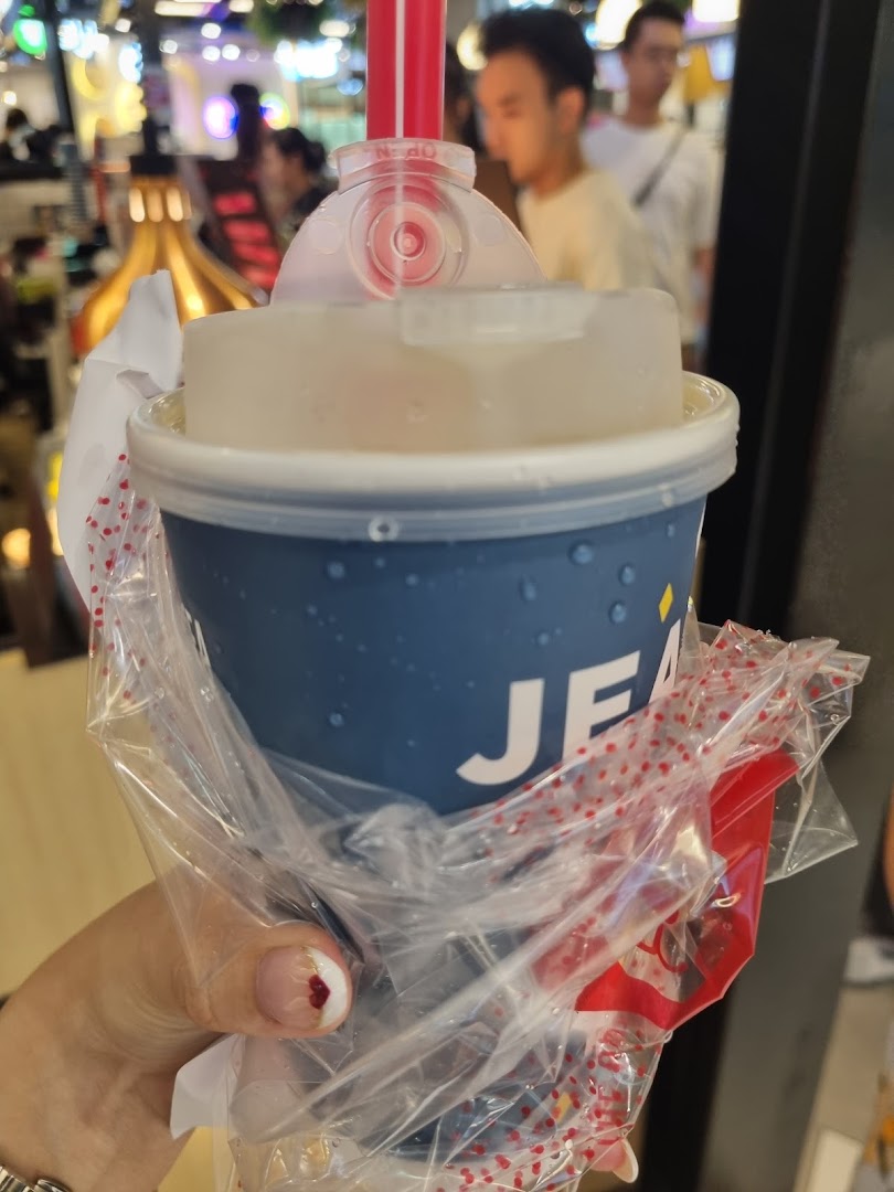 A hand holding a LiHO TEA beverage in a blue cup with a red straw.