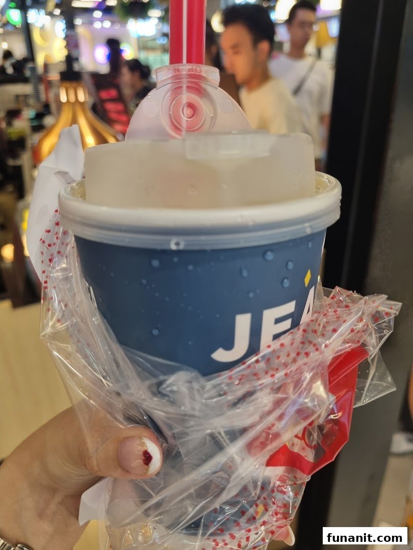 A hand holding a LiHO TEA beverage in a blue cup with a red straw.