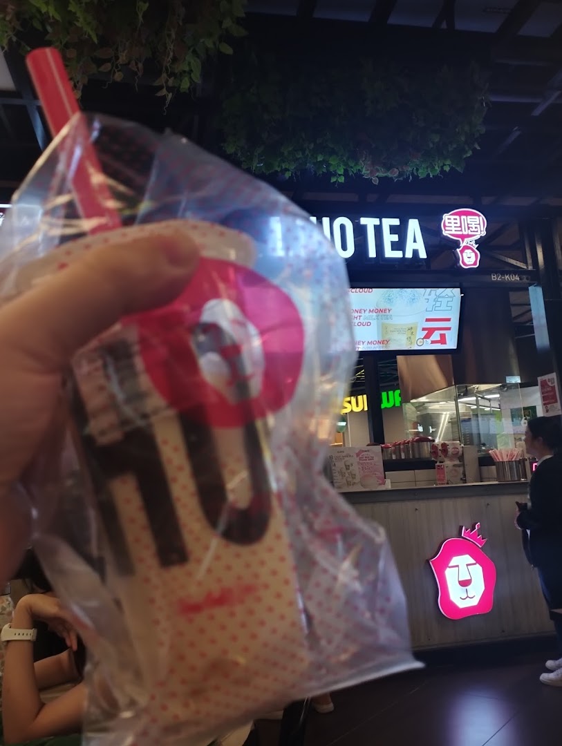 A customer holds a LiHO TEA bubble tea with the shop's counter and signage visible.