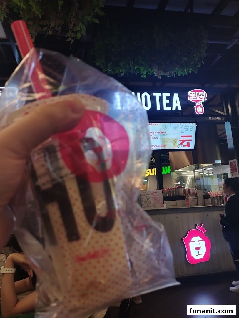 A customer holds a LiHO TEA bubble tea with the shop's counter and signage visible.