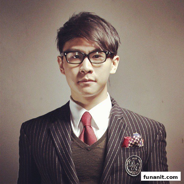 A stylishly dressed man in a pinstripe suit, white shirt, red tie, and glasses.