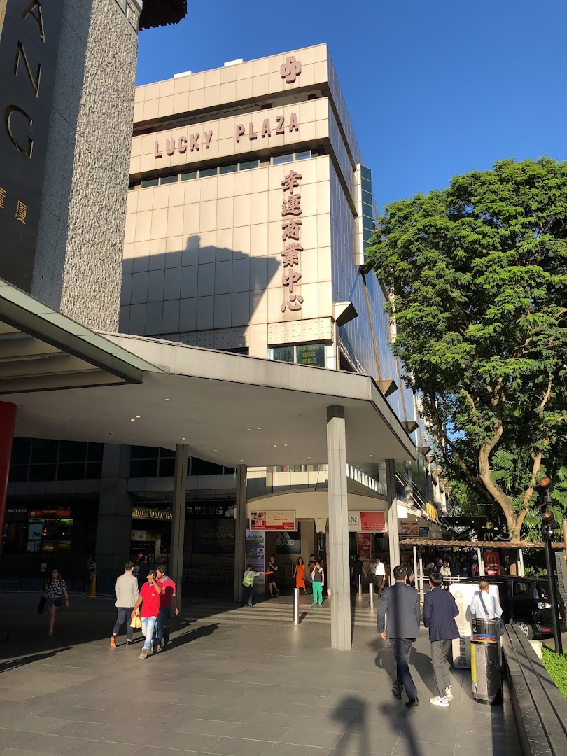 Exterior view of Lucky Plaza's entrance, showcasing the building facade and pedestrians.