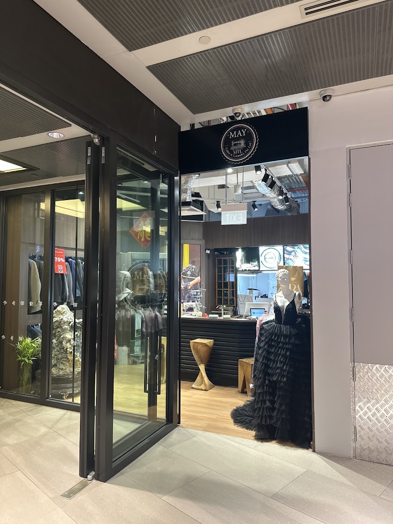 The shop front of May Tailor & Laundry, featuring a mannequin in a black ruffled dress.