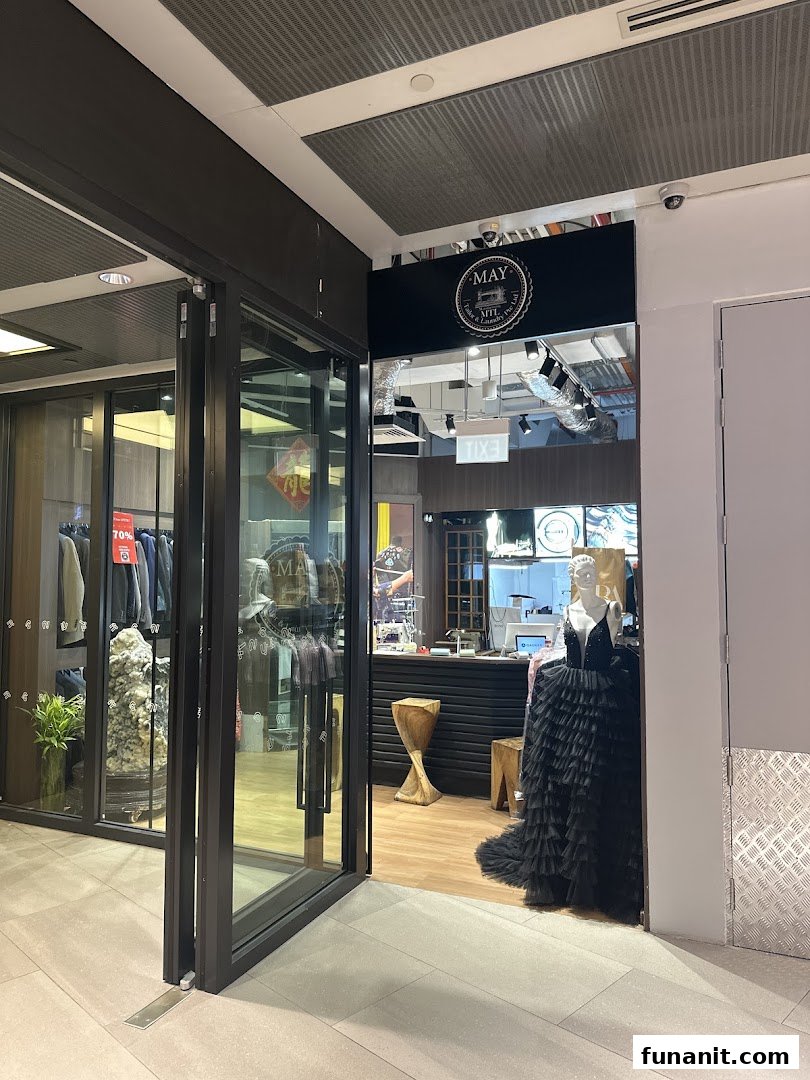 The shop front of May Tailor & Laundry, featuring a mannequin in a black ruffled dress.
