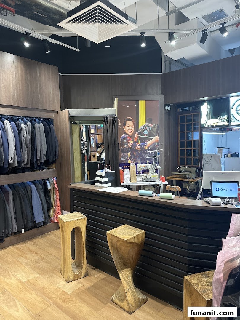Interior view of May Tailor Laundry, featuring clothing racks, a service counter, and a large promotional poster.
