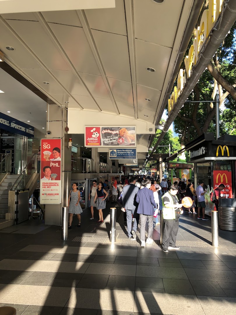 A bustling outdoor walkway featuring entrances to various retail and dining establishments like Jollibee and McDonald's.