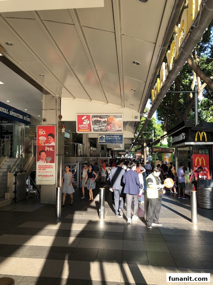 A bustling outdoor walkway featuring entrances to various retail and dining establishments like Jollibee and McDonald's.