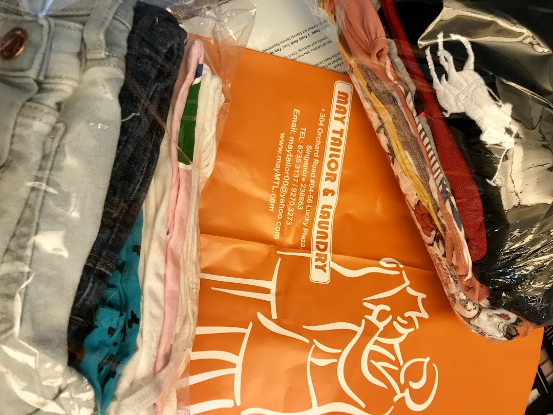 Freshly laundered or tailored clothes in clear packaging with a branded May Tailor & Laundry bag.