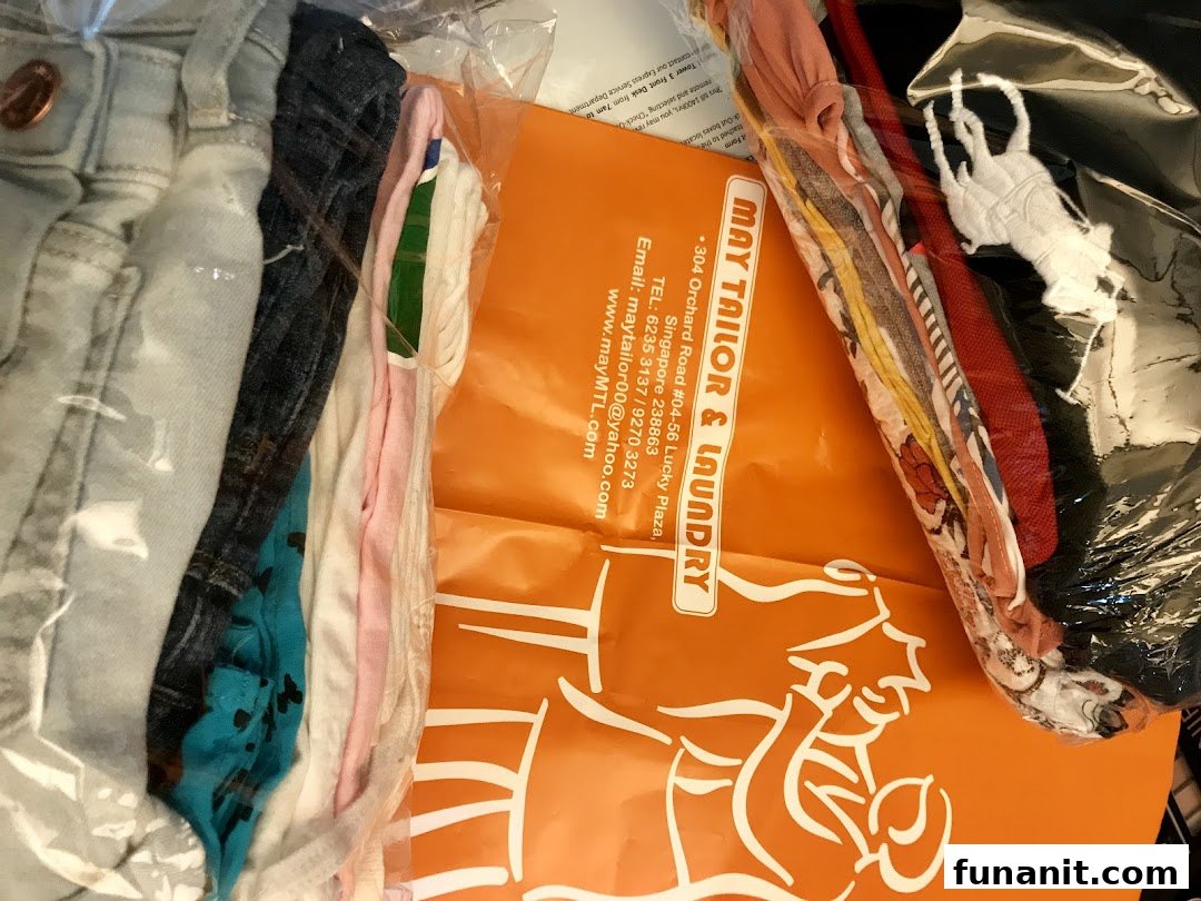 Freshly laundered or tailored clothes in clear packaging with a branded May Tailor & Laundry bag.