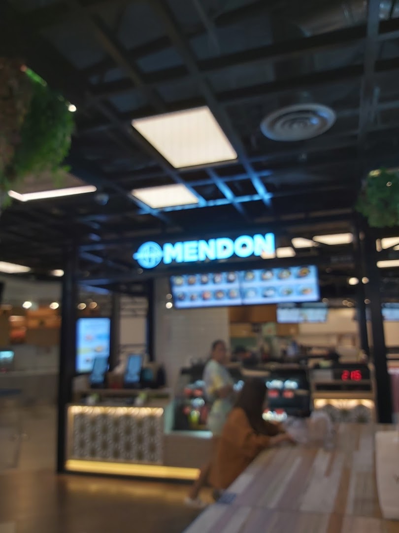 An interior view of Mendon, a food establishment, showing the counter, staff, and customers.