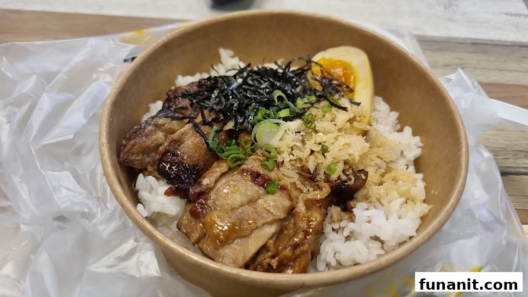 A close-up of a delicious rice bowl with grilled meat, a soft-boiled egg, and various toppings.