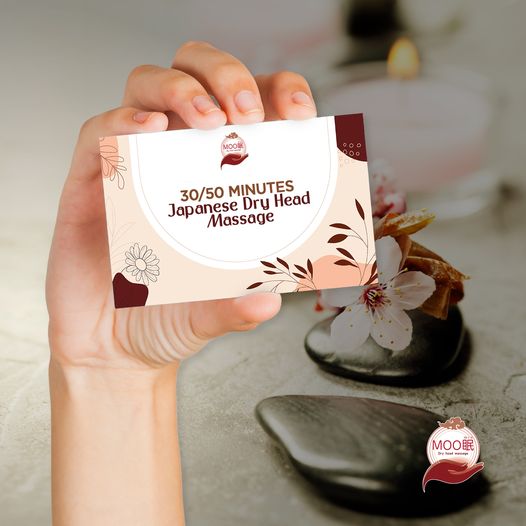 A hand holds a card advertising 30/50 minutes Japanese Dry Head Massage services.