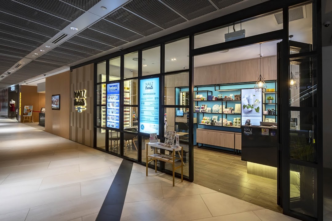 The brightly lit entrance of Nailz Treats salon, showcasing its modern interior and service displays from the mall corridor.