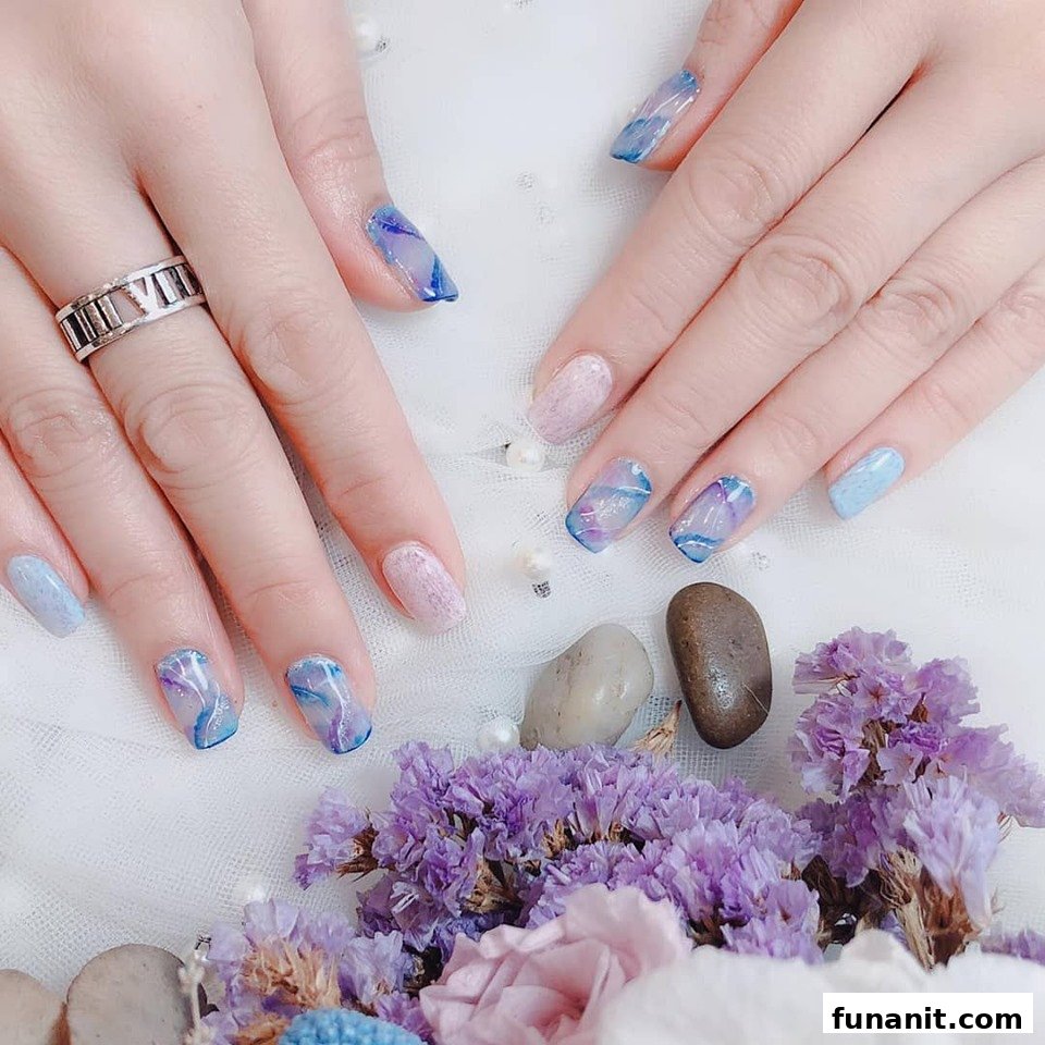 Close-up of hands showcasing intricate blue and purple marble nail art designs.
