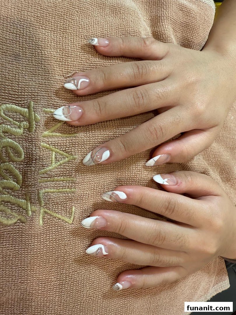 Close-up of hands showcasing a fresh, stylish nail art design with white and silver accents.