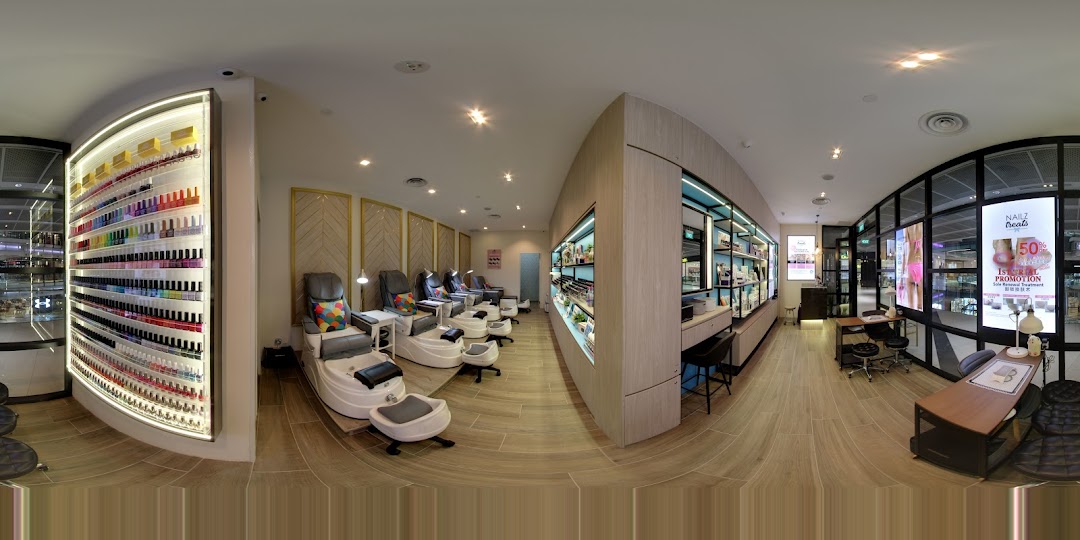 A panoramic view of a modern nail salon interior with pedicure chairs, nail polish displays, and manicure stations.
