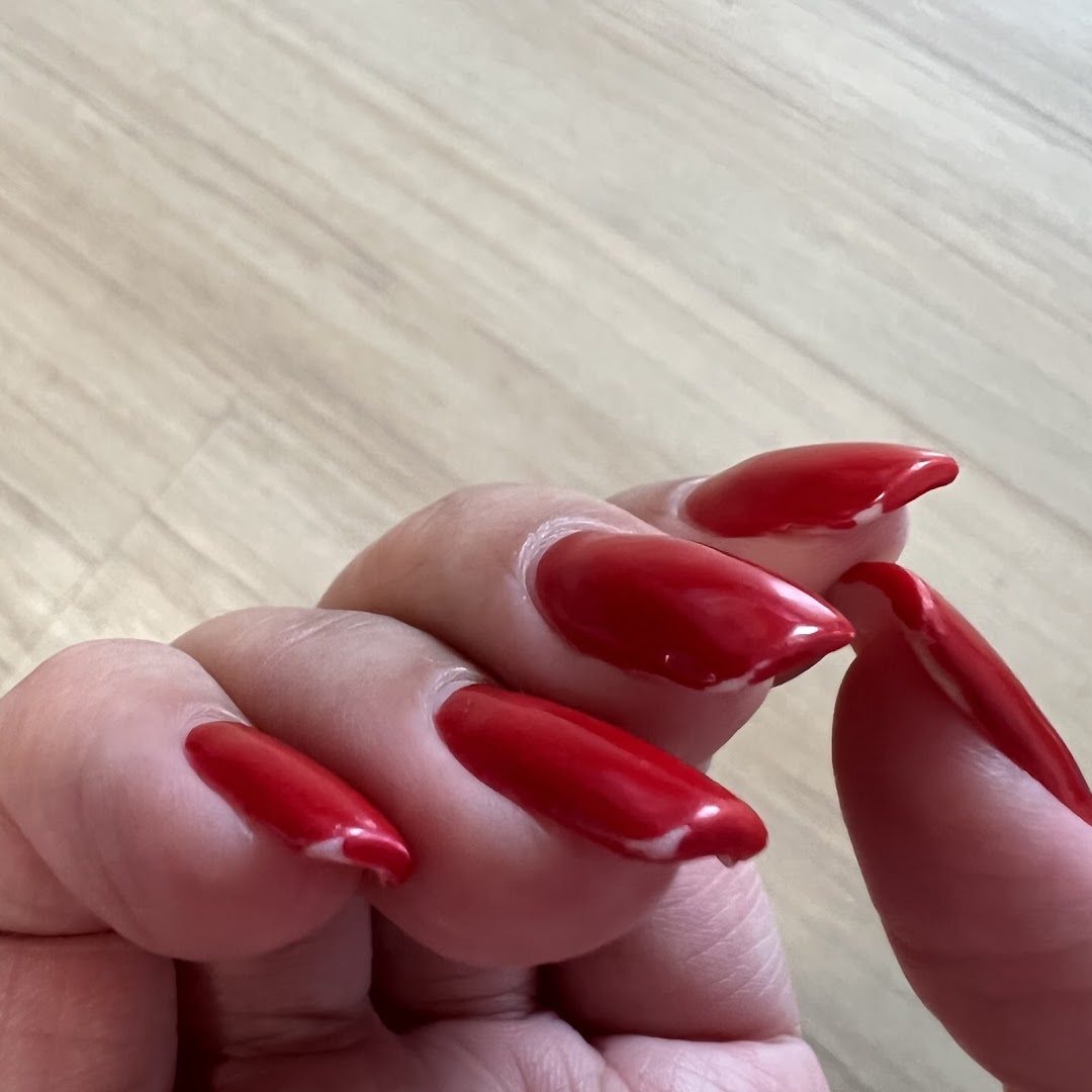 A close-up of a hand showcasing long, vibrant red manicured nails.