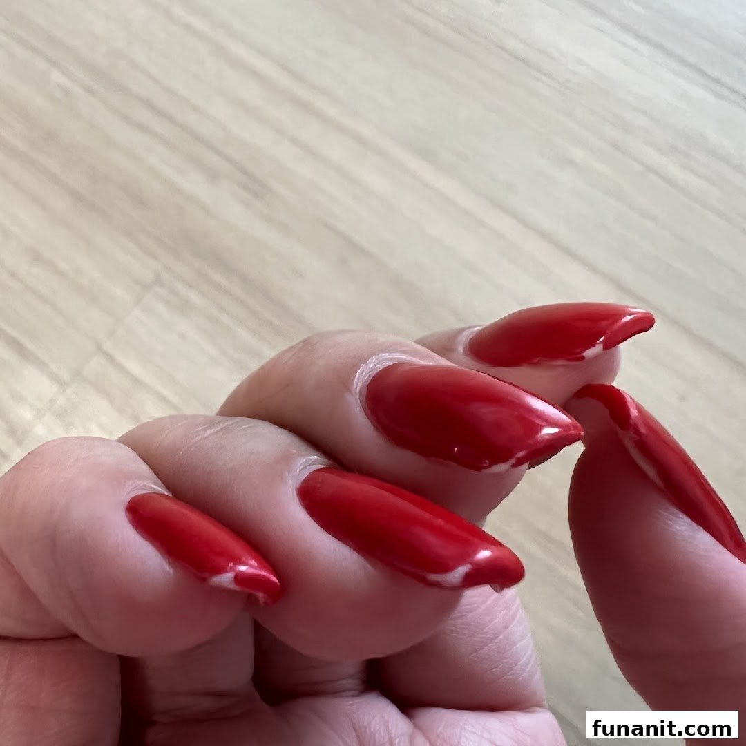 A close-up of a hand showcasing long, vibrant red manicured nails.