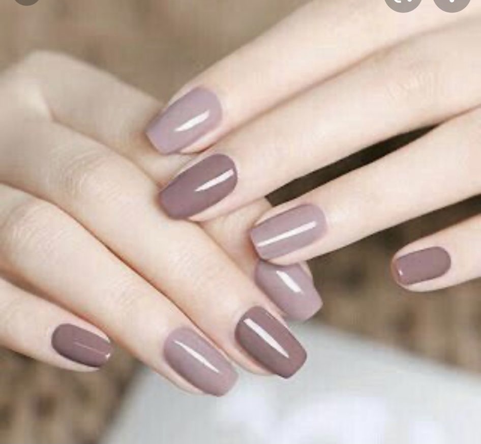 Close-up of hands showcasing a stylish two-tone manicure with brown and mauve nail polish.