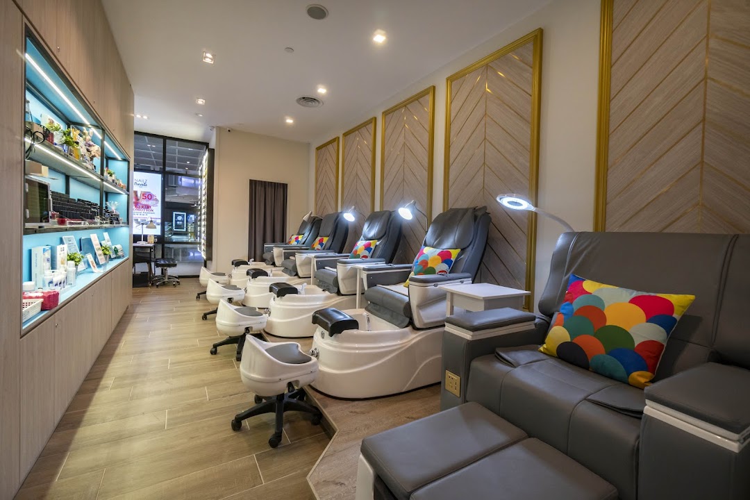 A modern nail salon interior featuring multiple comfortable pedicure stations with colorful cushions.