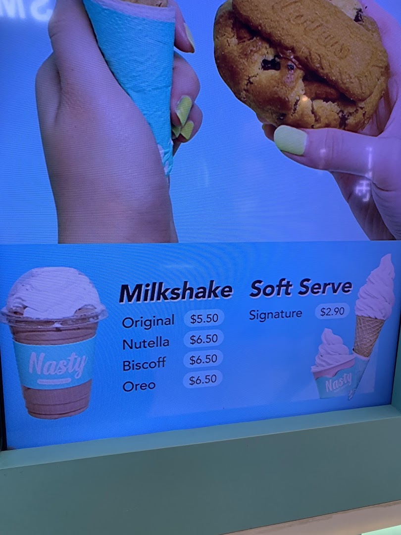 A digital menu board displaying milkshake and soft serve options with prices at Nasty Cookie.