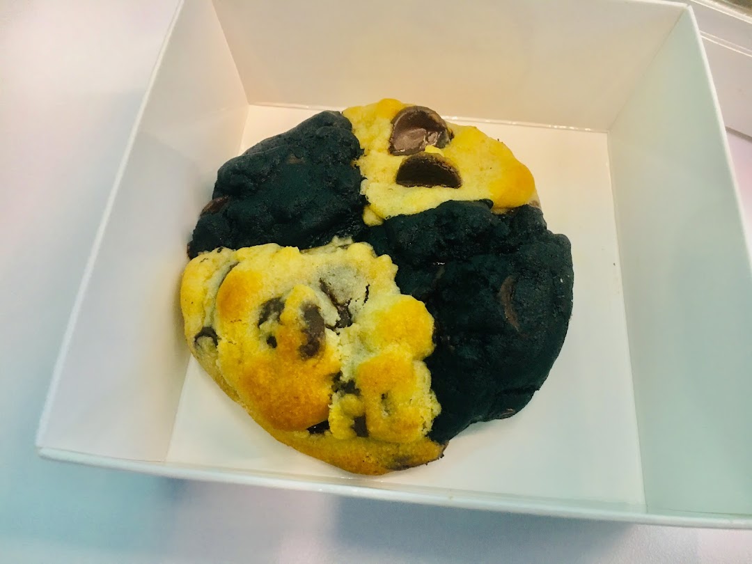 A large, dual-flavored cookie with chocolate chips in a white box.