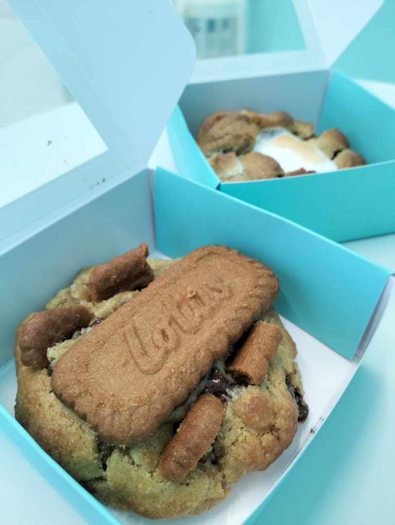 Two gourmet cookies in light blue boxes, one featuring a Lotus Biscoff topping.