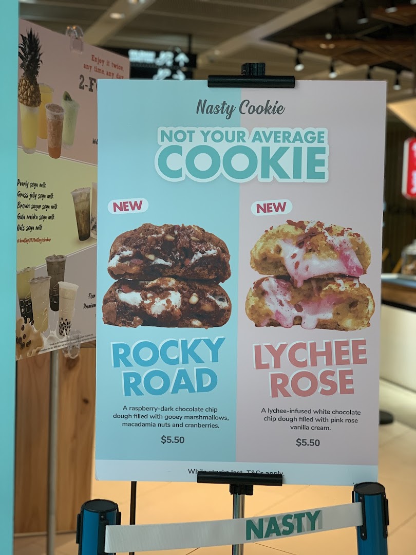 A display board showcasing Nasty Cookie's new Rocky Road and Lychee Rose cookie flavors with prices.