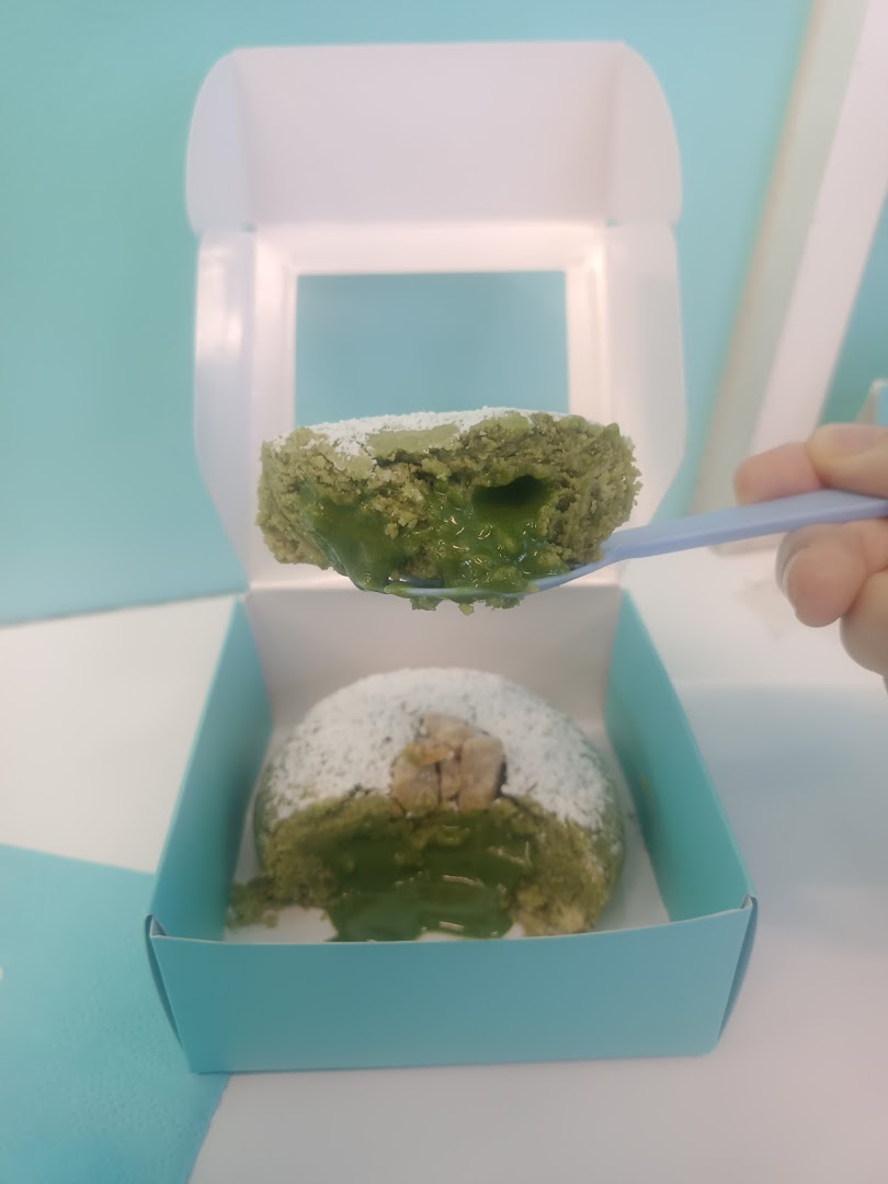 A matcha-flavored cookie with a gooey center being served from a box, showcasing its rich filling.