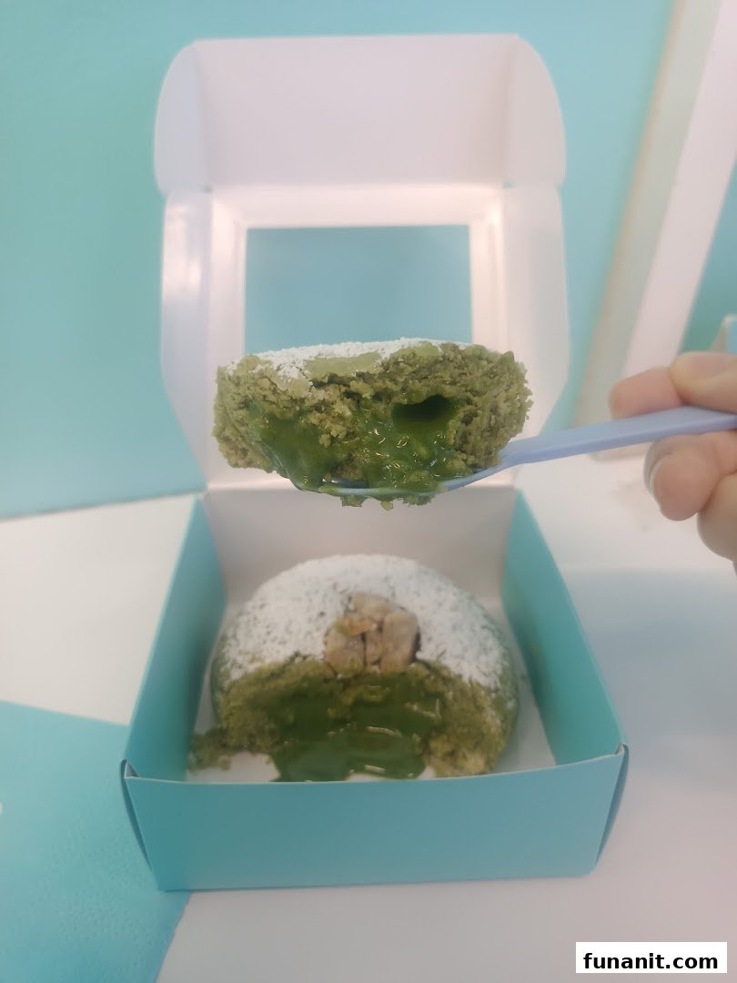 A matcha-flavored cookie with a gooey center being served from a box, showcasing its rich filling.