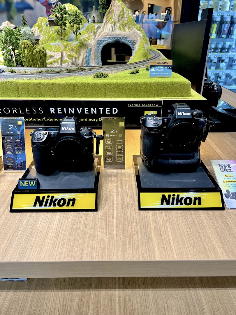 Two Nikon Z series cameras, Z8 and Z9, displayed on a counter with a miniature landscape backdrop.