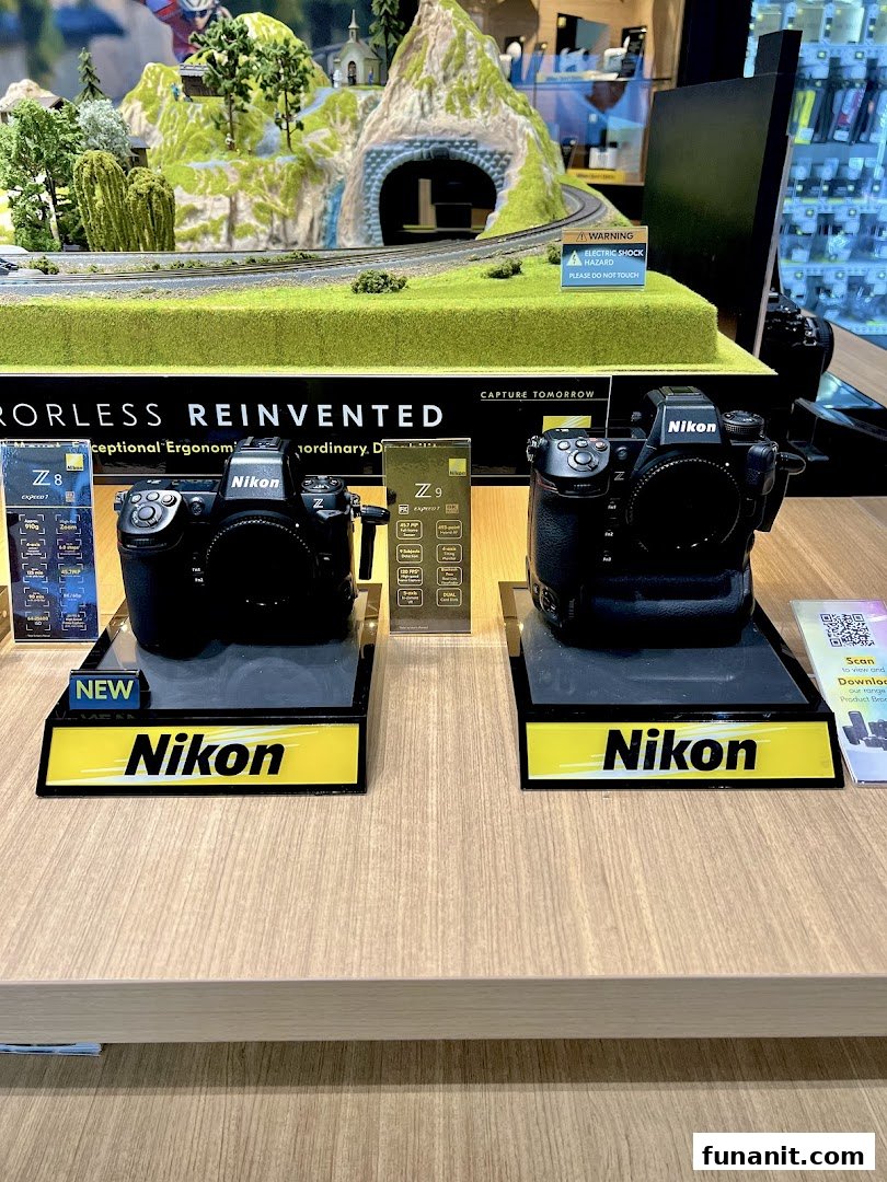 Two Nikon Z series cameras, Z8 and Z9, displayed on a counter with a miniature landscape backdrop.