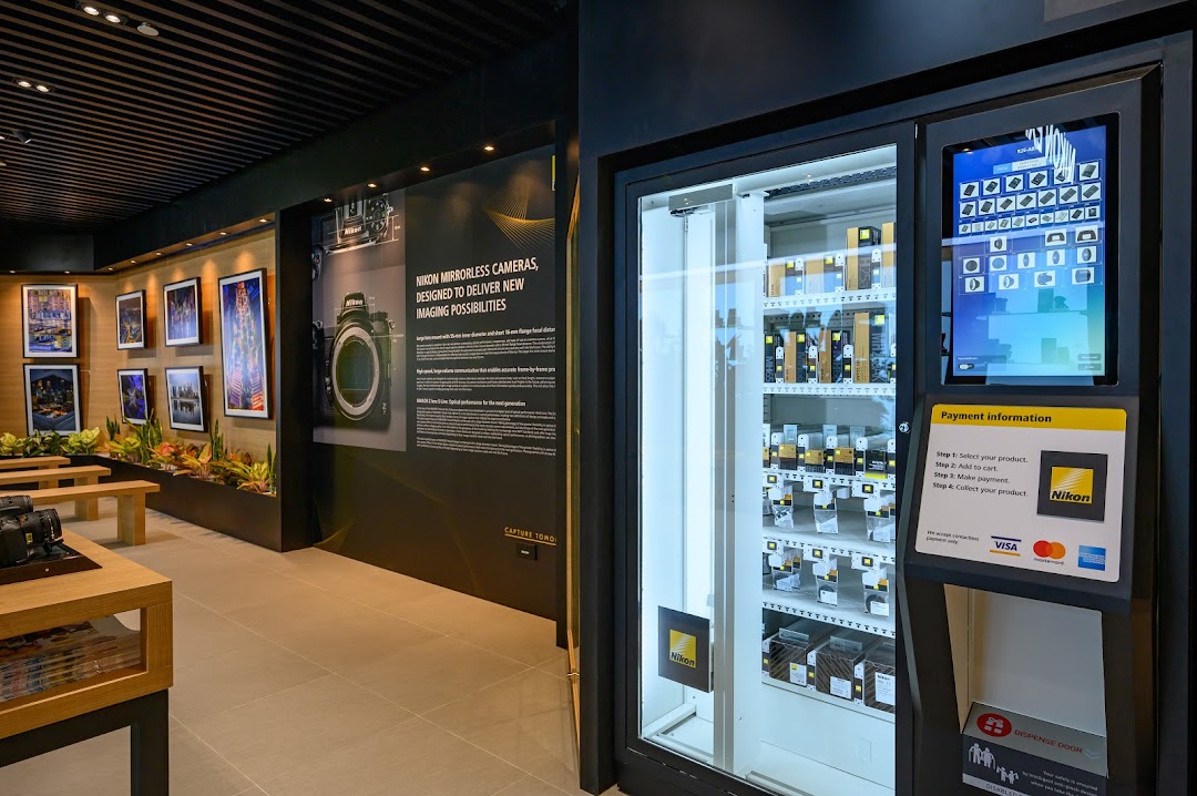 Interior view of Nikon Experience Hub featuring camera displays, product information, and a product vending machine.