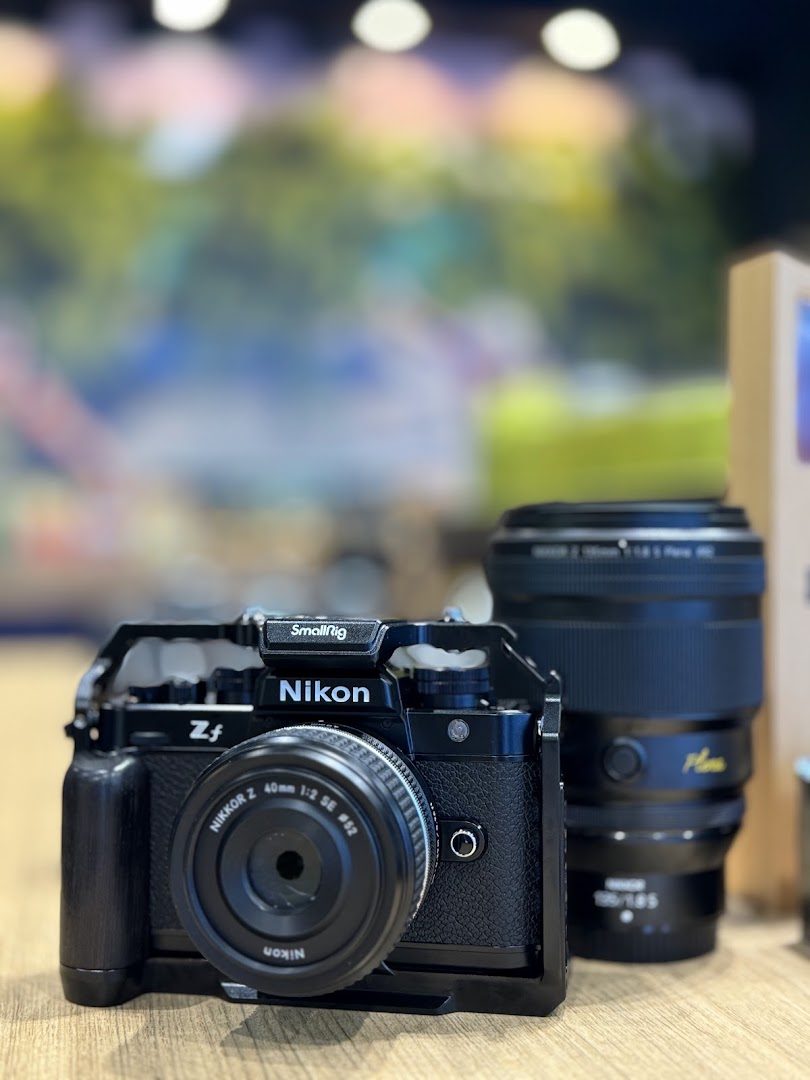 A close-up of a black Nikon Zf camera with a SmallRig cage and Nikkor Z 40mm lens.