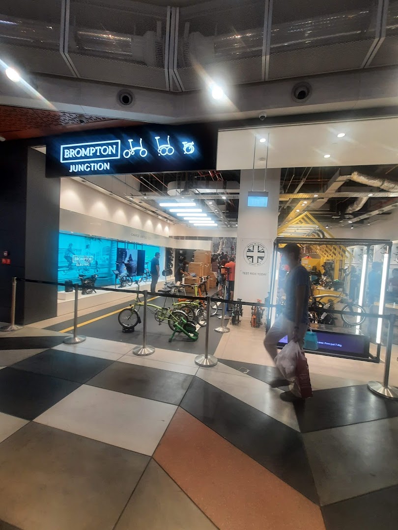 View of Brompton Junction shop entrance showcasing folding bikes on display, with a person walking past.