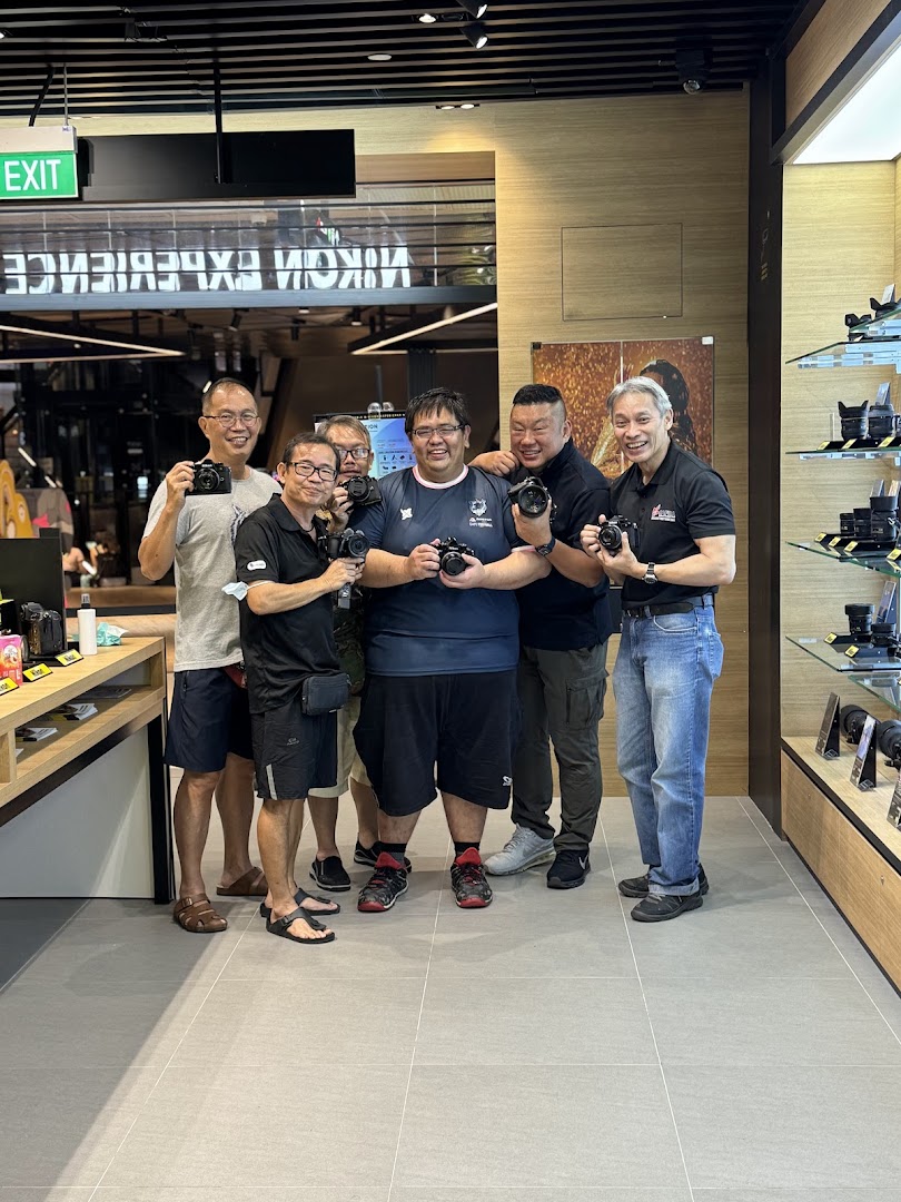 A group of smiling men holding cameras inside the Nikon Experience Hub Singapore.