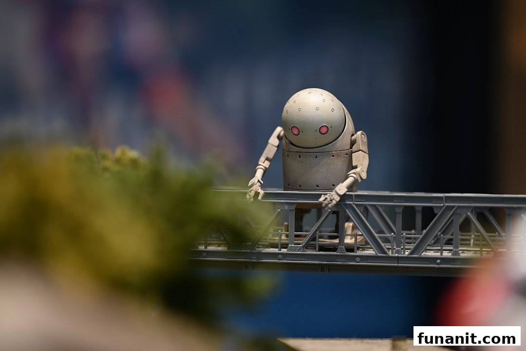 A detailed miniature robot figure with red eyes stands on a model bridge, showcasing intricate detail.