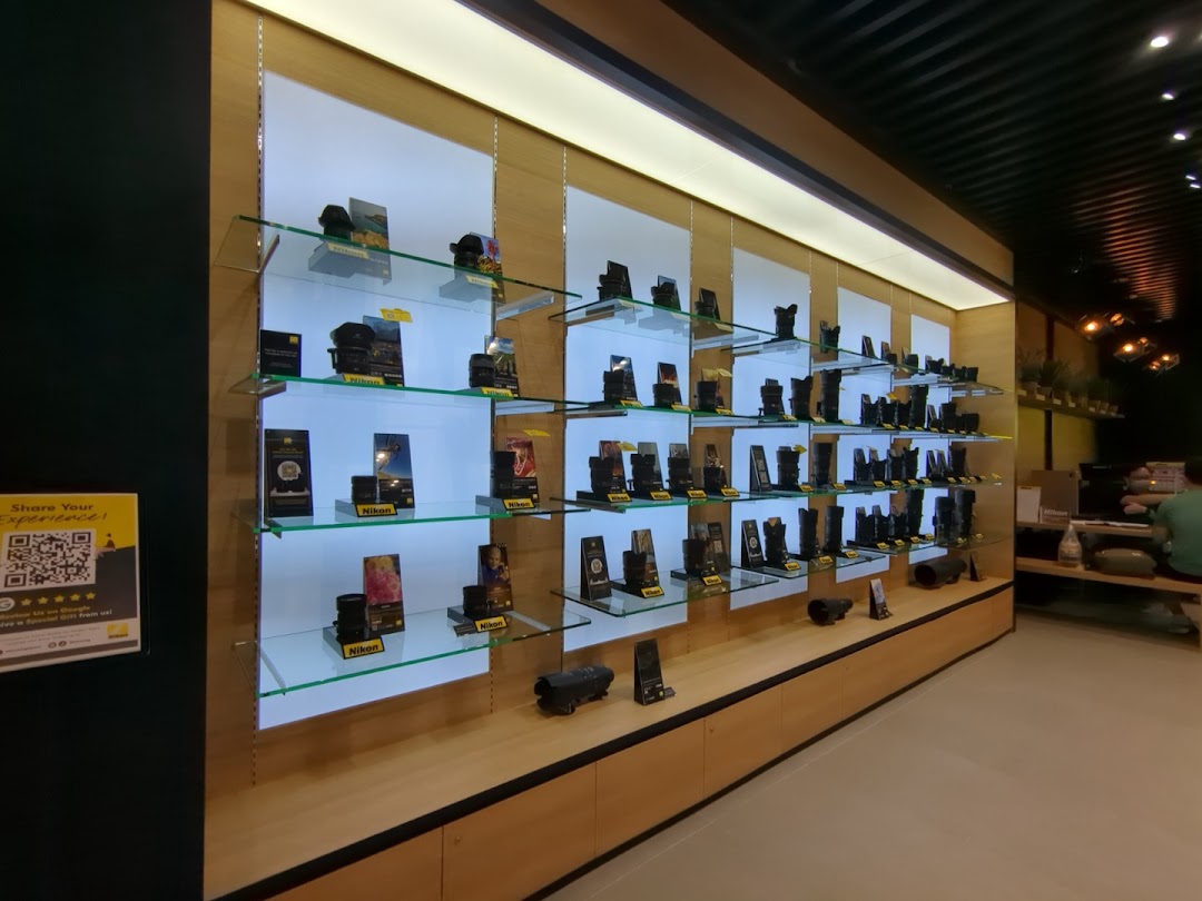 An interior view of the Nikon Experience Hub, showcasing a wide array of camera lenses and accessories on illuminated shelves.