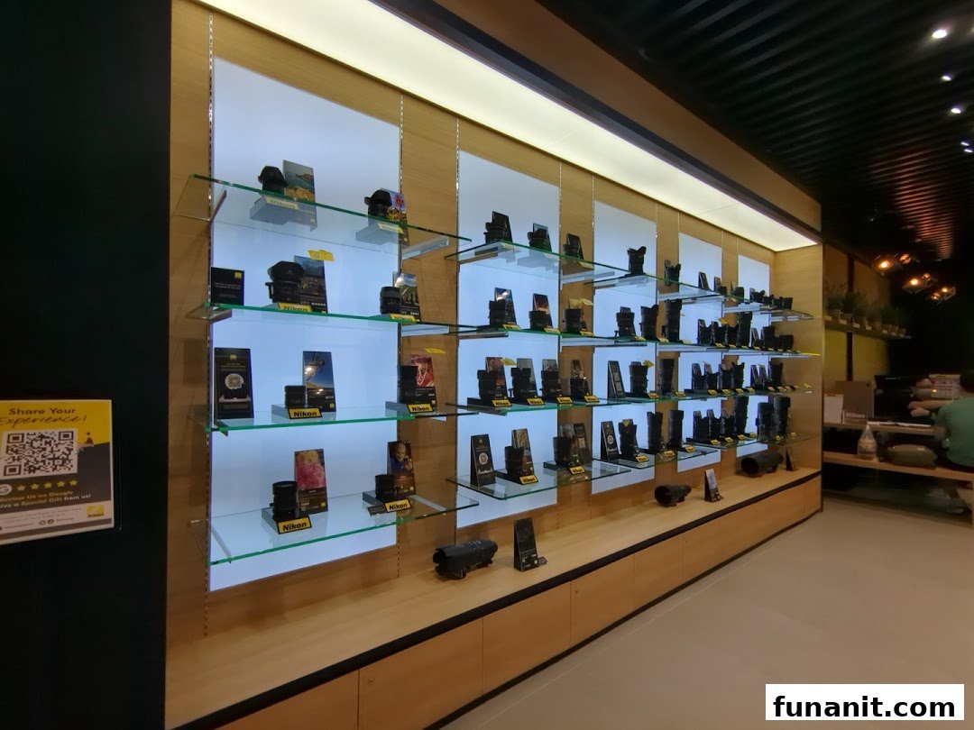 An interior view of the Nikon Experience Hub, showcasing a wide array of camera lenses and accessories on illuminated shelves.