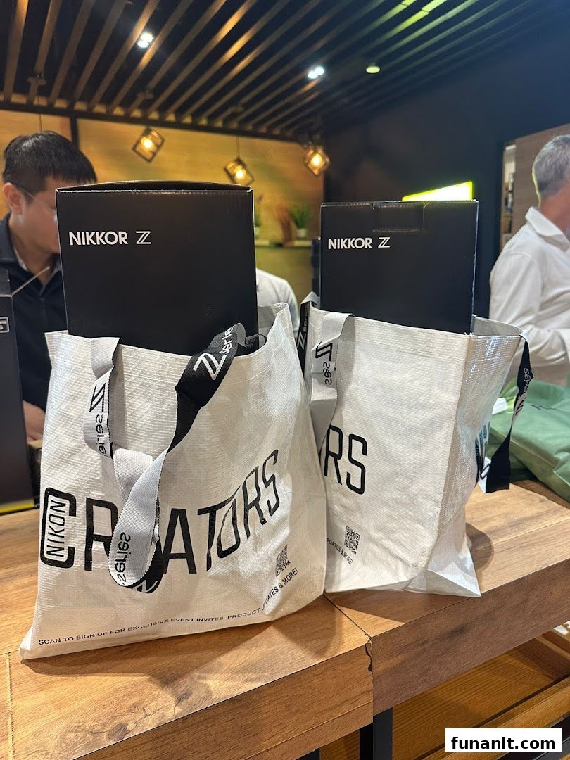 Two Nikon-branded shopping bags with NIKKOR Z product boxes on a wooden counter inside the store.