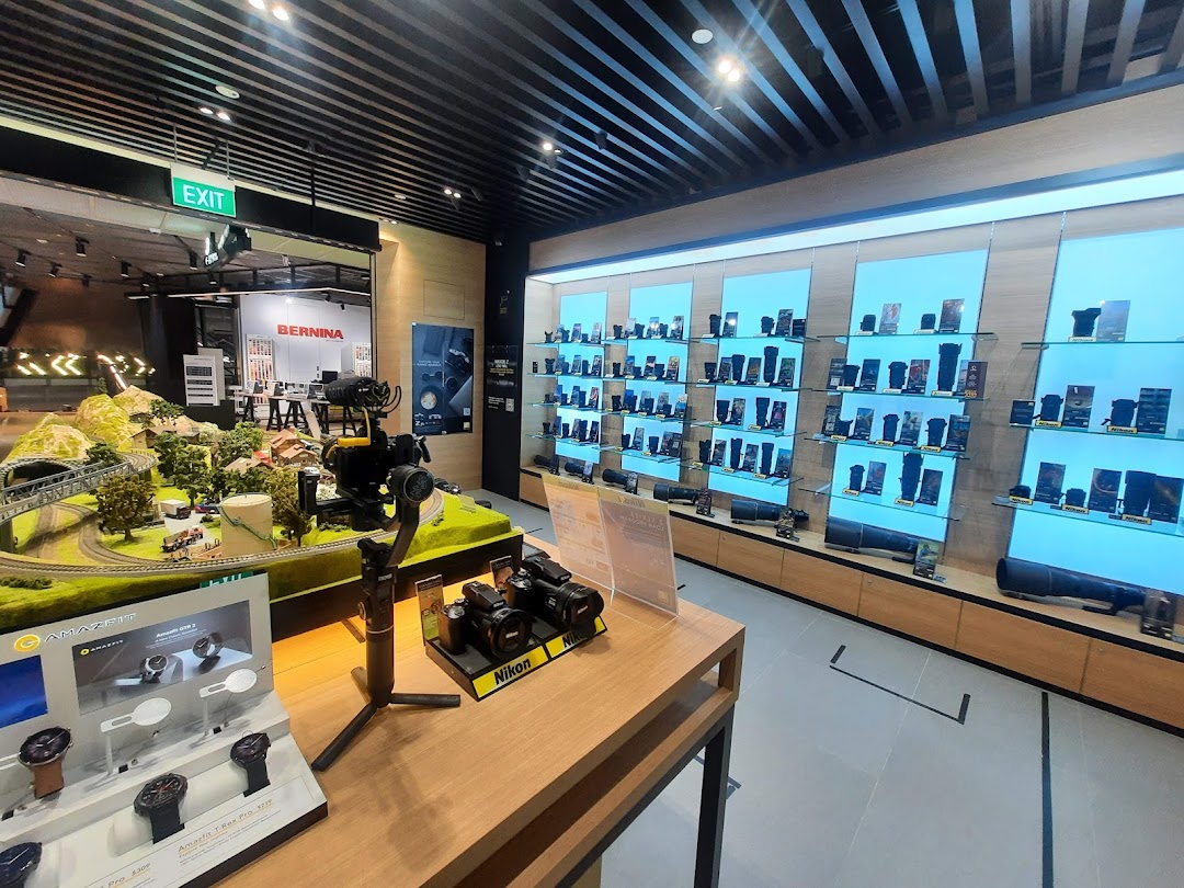 Interior view of Nikon Experience Hub, showcasing cameras, lenses, and electronics displays, with a model train set.