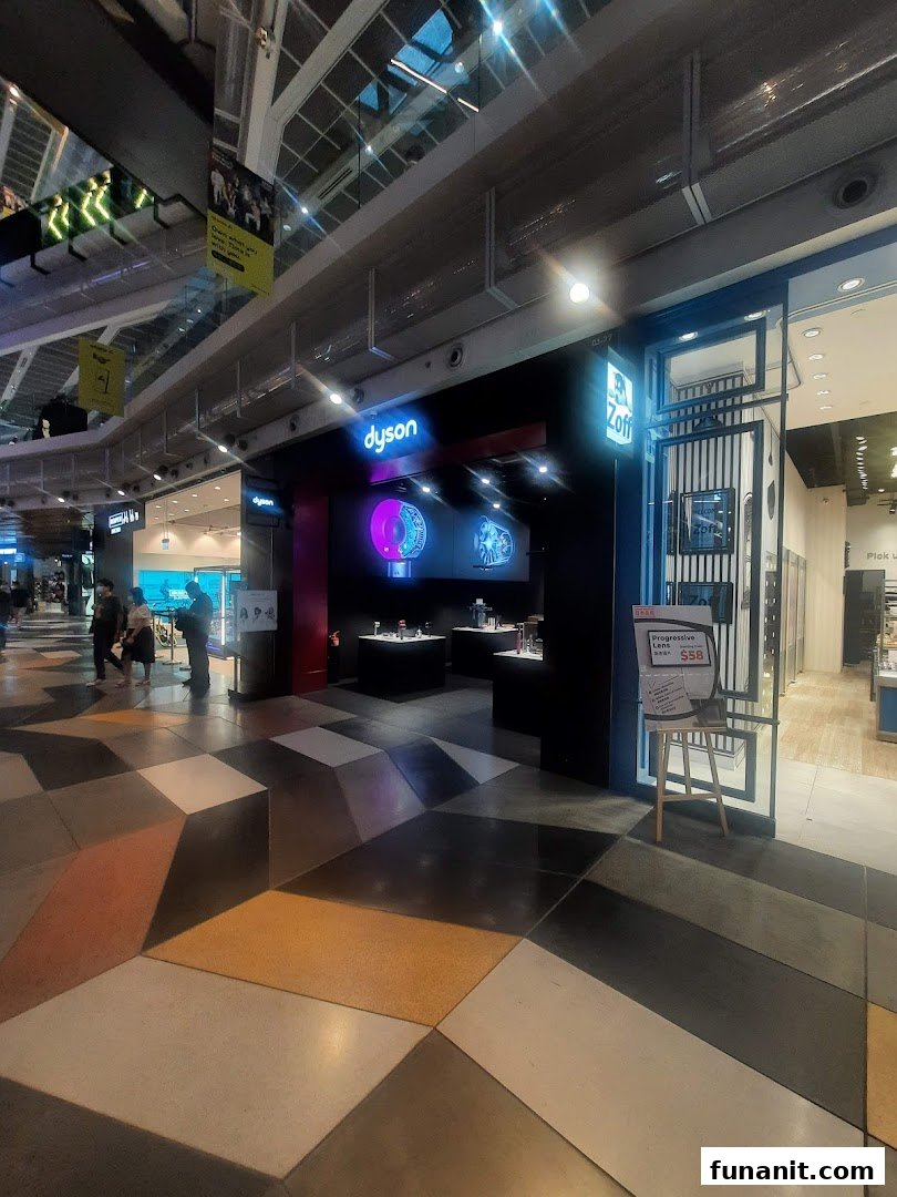 The image captures the illuminated entrance of a Dyson store, showcasing its innovative products, adjacent to Zoff eyewear.