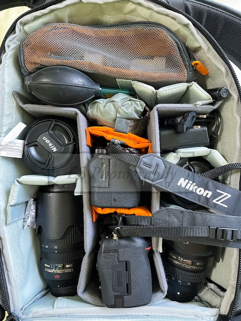 A camera bag filled with Nikon DSLR and mirrorless cameras, lenses, and essential accessories.