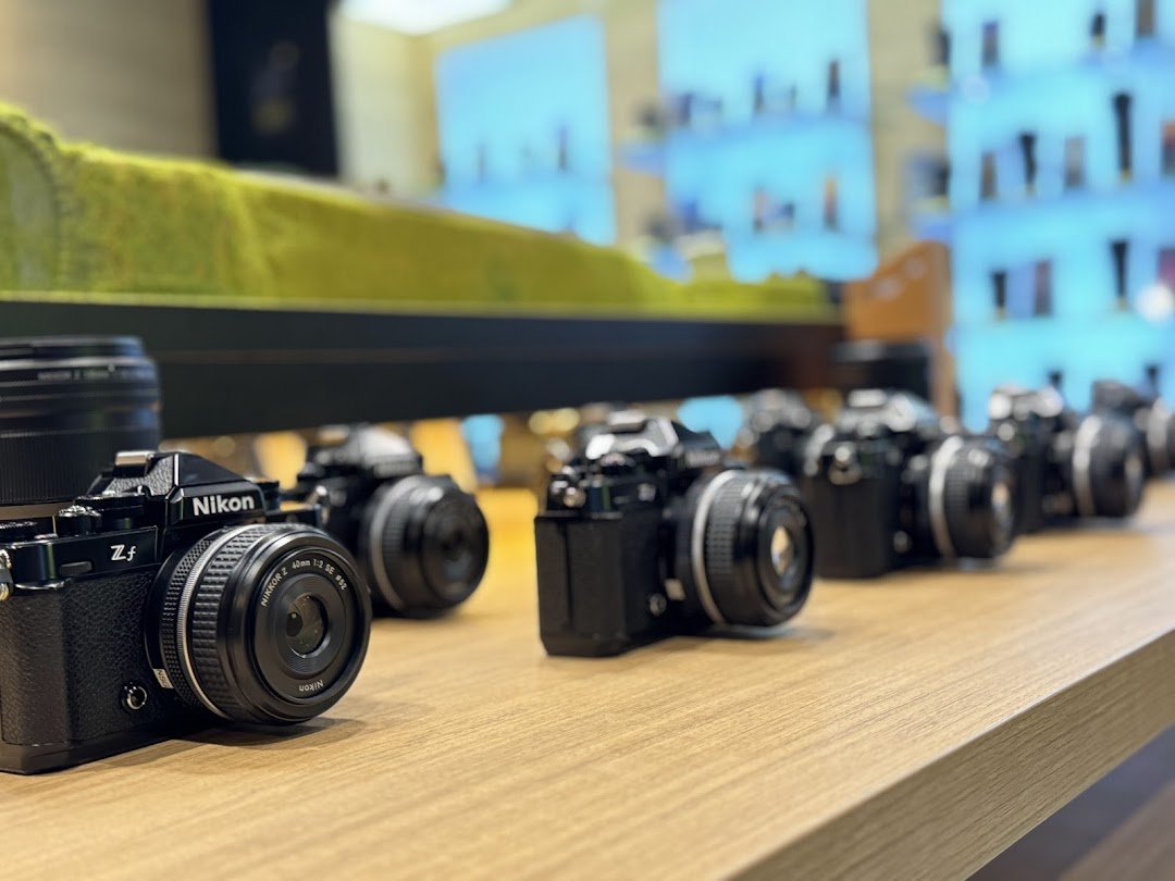 A row of sleek Nikon Z f cameras displayed on a wooden counter inside the Nikon Experience Hub.