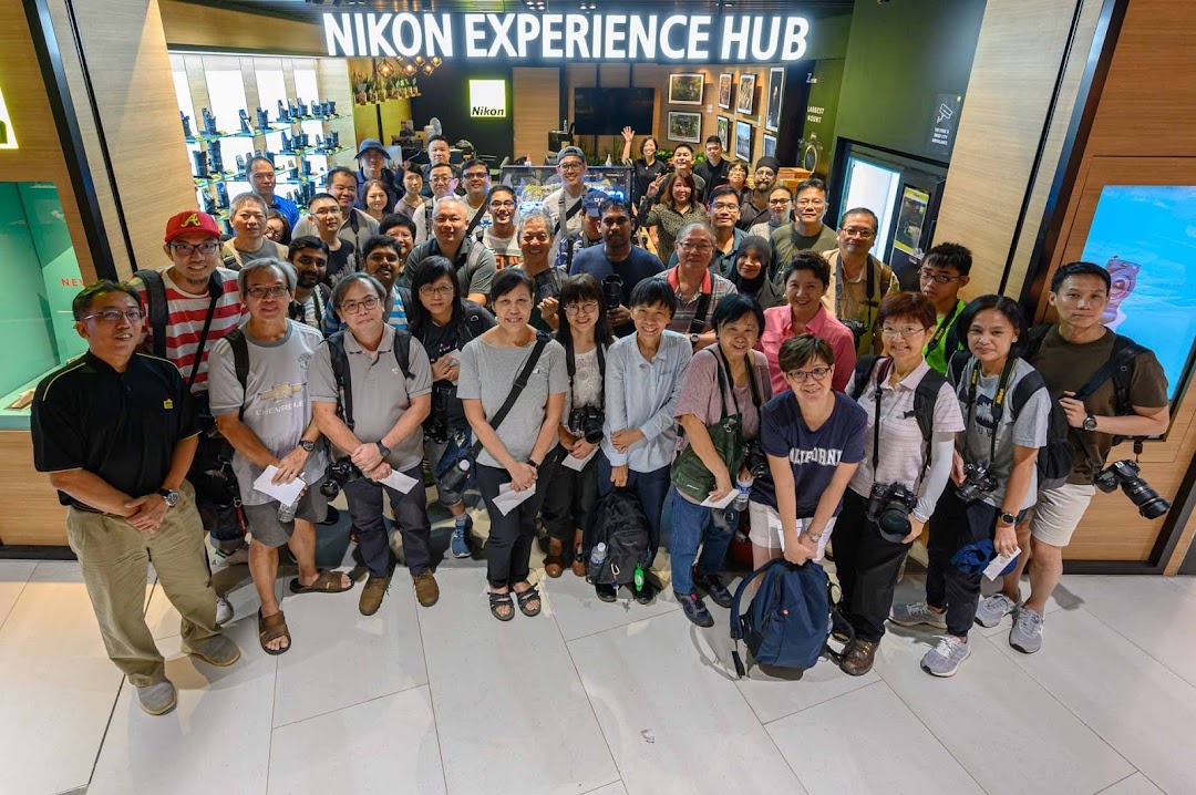 A large group of photography enthusiasts poses in front of the Nikon Experience Hub Singapore.