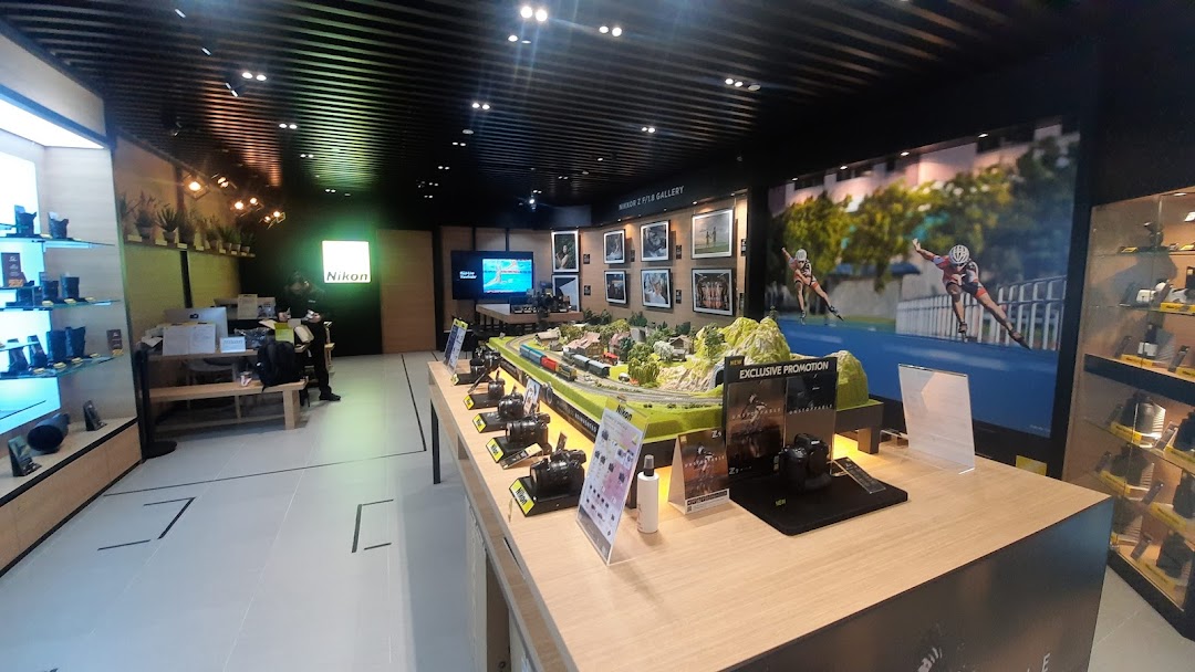 Interior view of Nikon Experience Hub, showcasing cameras, lenses, a model train display, and a photo gallery.