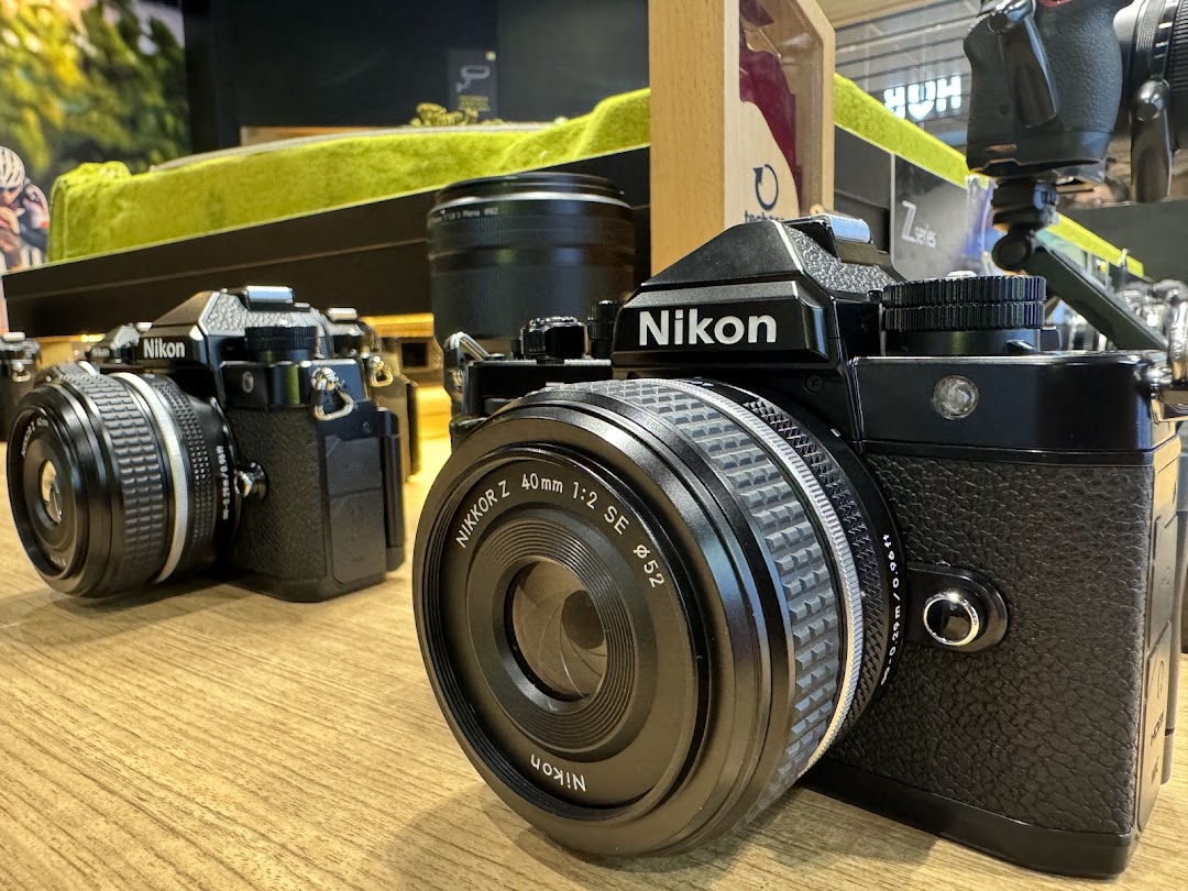 Close-up of two classic Nikon cameras with lenses displayed on a wooden counter inside the shop.