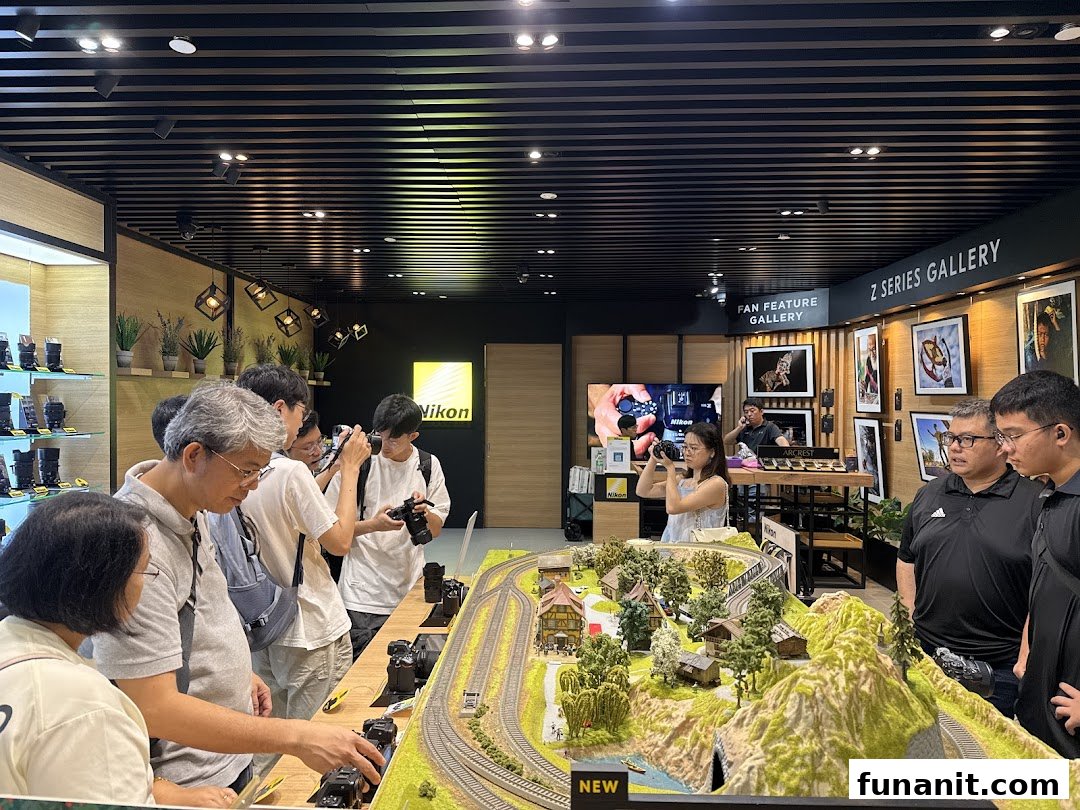 Visitors engage with Nikon cameras at an interactive display featuring a miniature landscape and product galleries.
