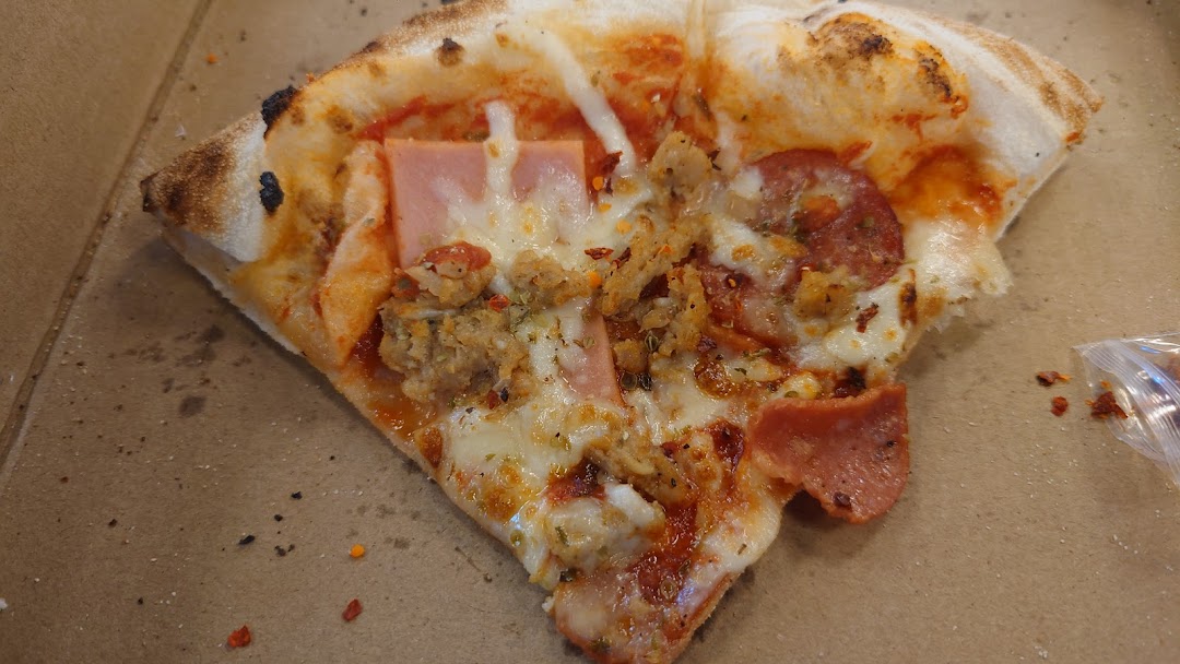 A close-up of a delicious, well-topped pizza slice resting in a cardboard box.